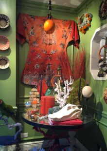 Interior with green wall, woven baskets, red silk kimono, table with mounted coral, alligator skull, mounted ostrich egg, and glass jellyfish