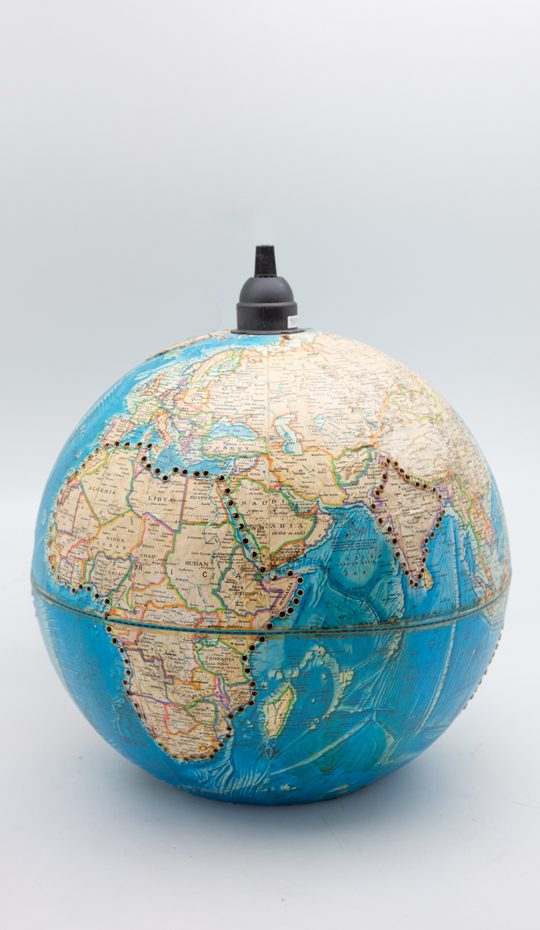 Close-up on a blue spherical globe with yellow card. Black button on the top for the cord