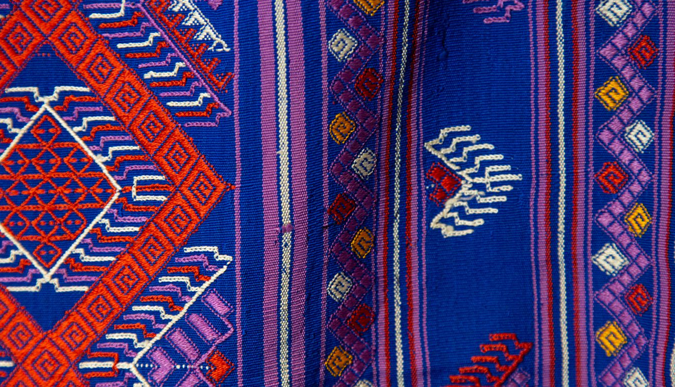 closeup of Large Blue Textile with red and white diamond zig-zag pattern with multicolor geometric designs