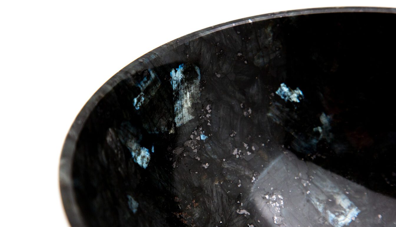 close-up on a black bowl of labradorite on a white background