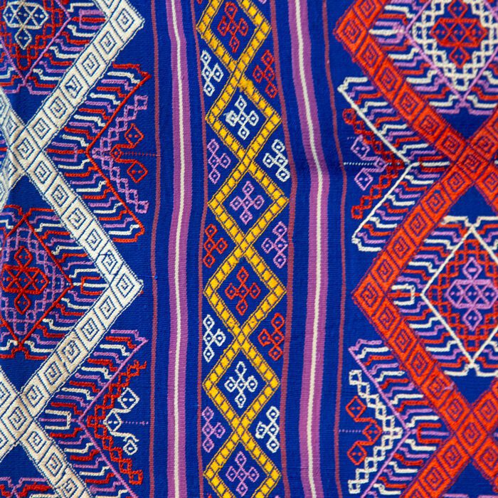 closeup of Large Blue Textile with red and white diamond zig-zag pattern with multicolor geometric designs