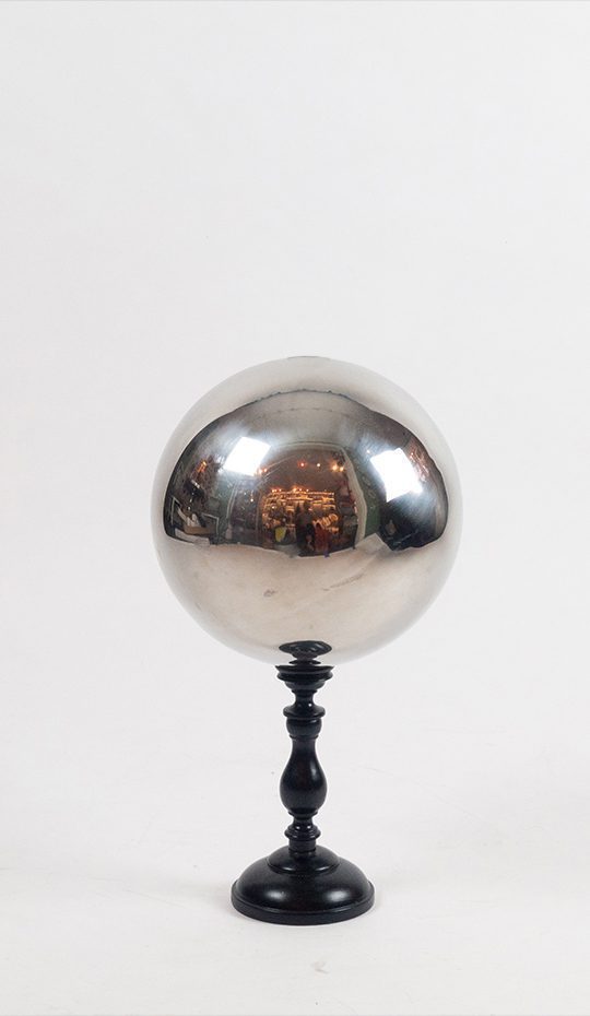 A stainless steel butler's ball mounted on a turned wooden base.